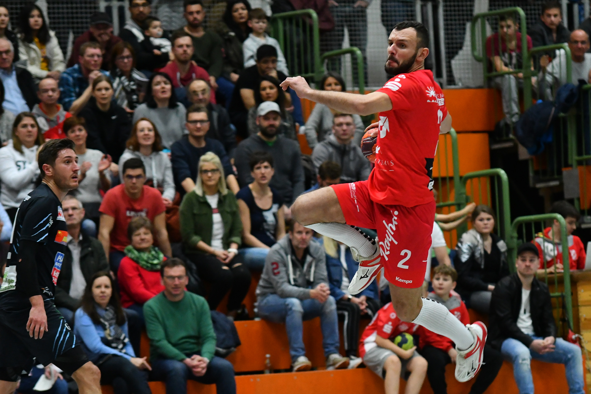 Handballspieler im Wurf, Zuschauer im Hintergund